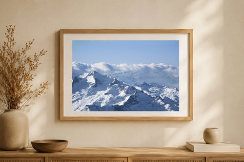 Tirage photographique encadré d’une vue aérienne des Pyrénées enneigées présenté dans un intérieur lumineux.