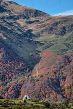 Photographie du Courtaou des Esclozes dans les Hautes-Pyrénées en automne, avec une maison traditionnelle entourée de montagnes aux couleurs automnales.